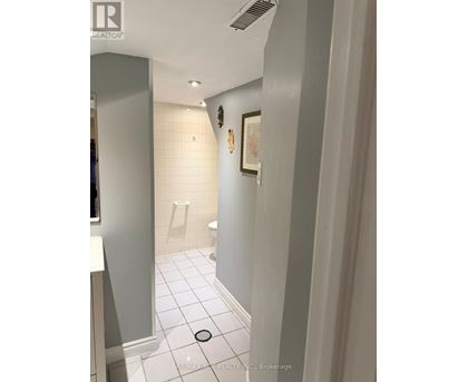 A bathroom with a toilet, sink, and a picture on the wall.