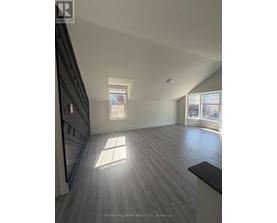 A spacious room with wooden flooring and a skylight.