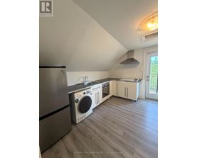 A kitchen with a stainless steel refrigerator and a washing machine built into the cabinetry.