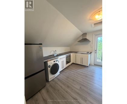 A kitchen with a stainless steel refrigerator and a washing machine built into the cabinetry.