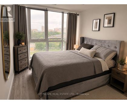 A bedroom with a large bed, a dresser, and a window with a view of the city.