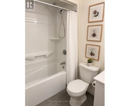 A white toilet in a bathroom with a white tub and shower curtain.
