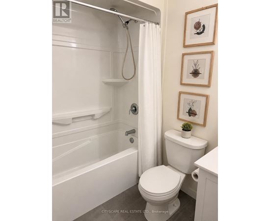 A white toilet in a bathroom with a white tub and shower curtain.