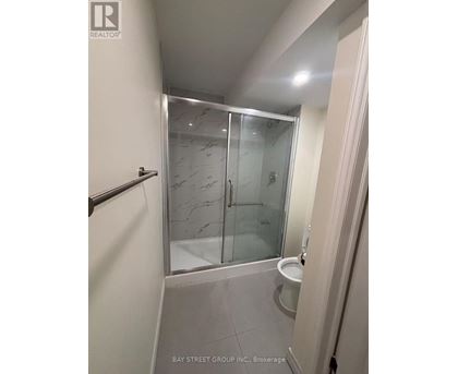 A bathroom with a glass shower door and a toilet.
