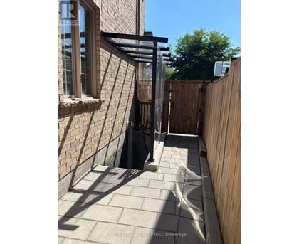 A sunny day at a Bay Street Group Inc. Brokerage property with a wooden fence and a brick wall.