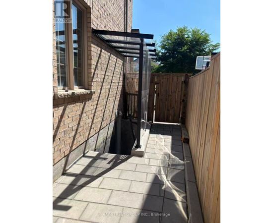 A sunny day at a Bay Street Group Inc. Brokerage property with a wooden fence and a brick wall.