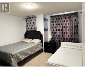 A bedroom with a bed, nightstand, and window with curtains.