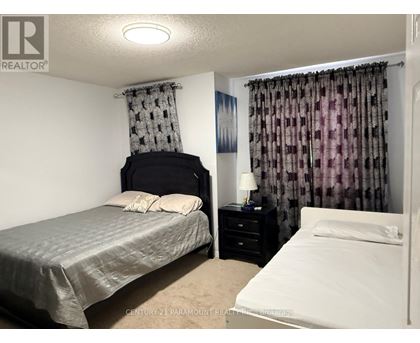 A bedroom with a bed, nightstand, and window with curtains.