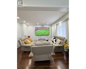 A living room with a large screen TV and comfortable seating.