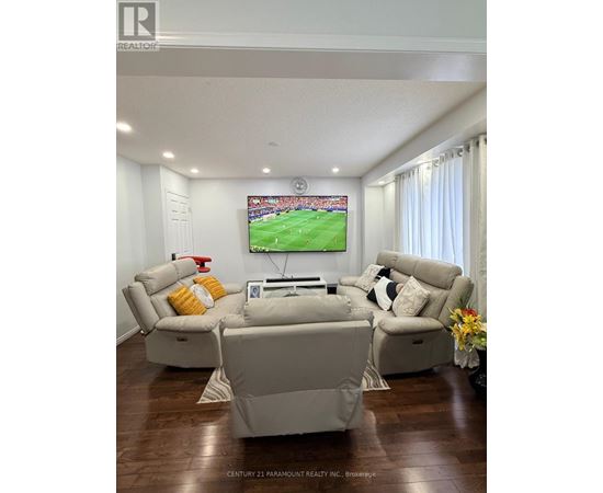 A living room with a large screen TV and comfortable seating.