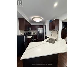A kitchen with a marble countertop and dark brown cabinets.