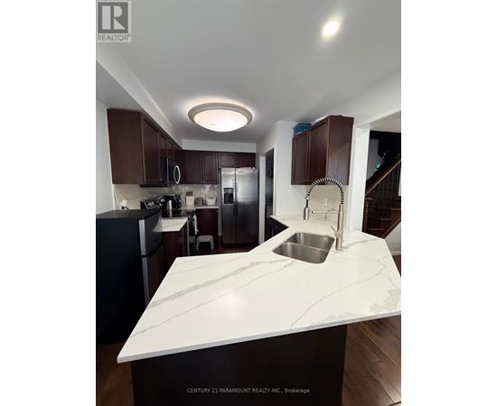 A kitchen with a marble countertop and dark brown cabinets.