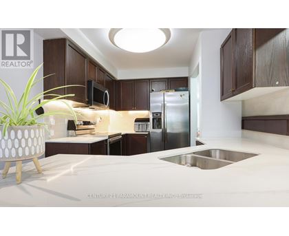 A modern kitchen with dark brown cabinets and a stainless steel refrigerator.