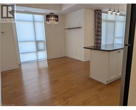 A room with wooden floors and a large window with a chandelier hanging from the ceiling.