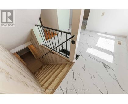 A staircase with a wooden handrail and a marble floor.