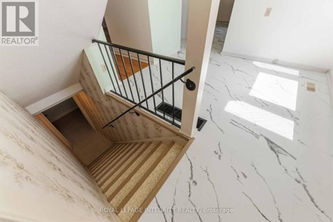 A staircase with a wooden handrail and a marble floor.