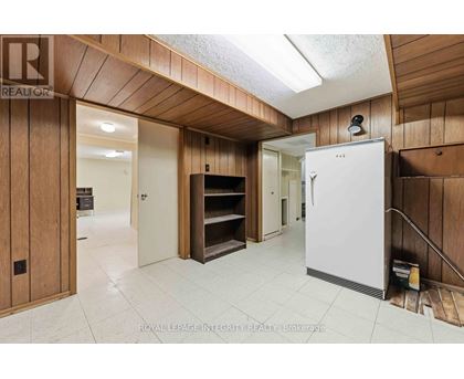 A white refrigerator is in a kitchen with wooden walls.