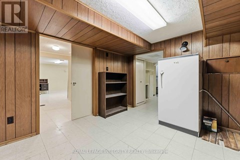 A white refrigerator is in a kitchen with wooden walls.