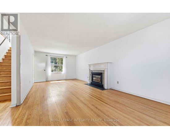 A spacious room with a fireplace and wooden flooring.