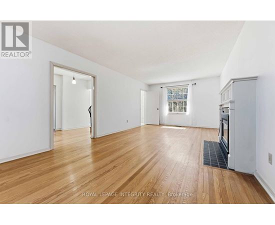 A spacious room with wooden flooring and white walls.
