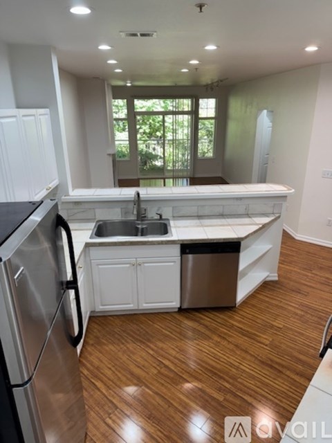 A modern kitchen with a stainless steel refrigerator and a wooden floor.