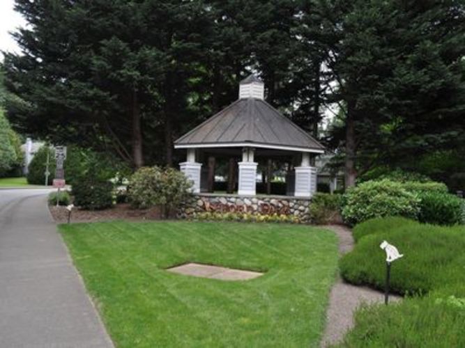 A gazebo is surrounded by a grassy area and a stone wall.