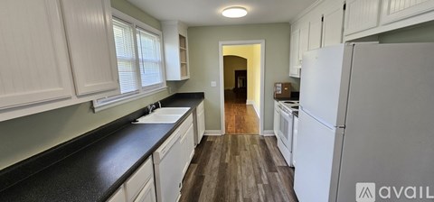 A kitchen with white cabinets and a black countertop.