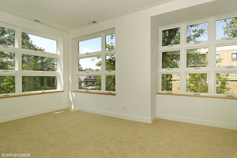 A room with two windows and carpeted flooring.