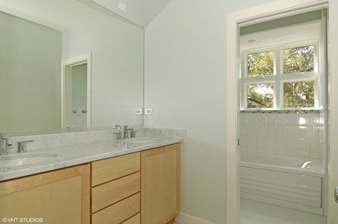 A bathroom with a white counter top and a window with a view of trees.