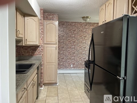 A kitchen with a black refrigerator and wooden cabinets.