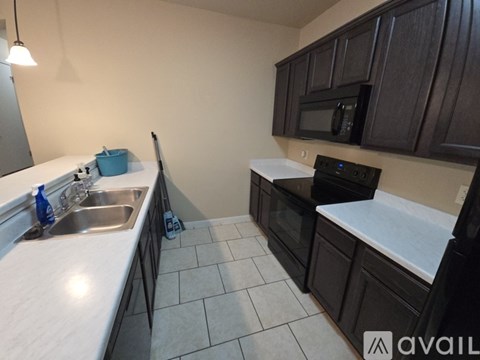 A kitchen with dark brown cabinets and a white countertop.