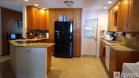 A kitchen with wooden cabinets and a black refrigerator.