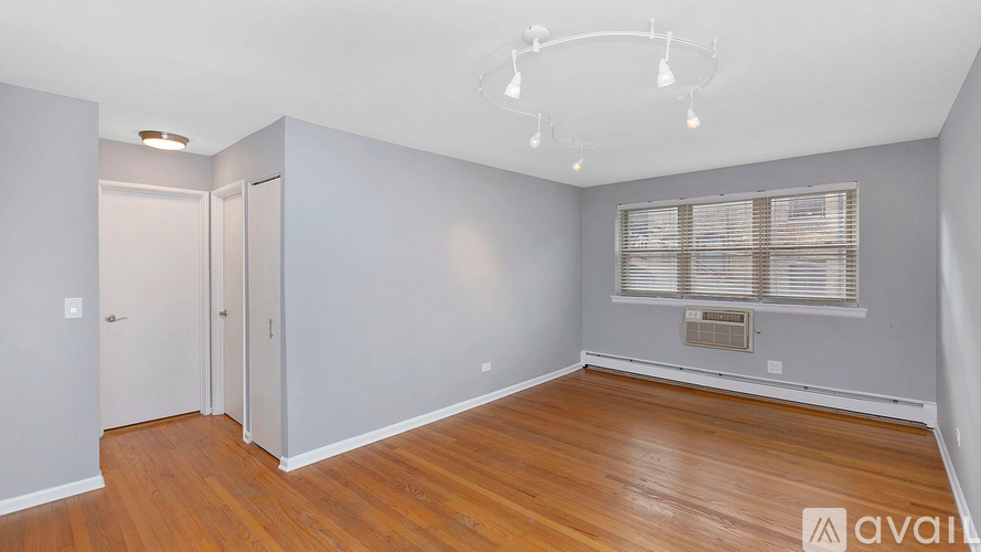 A room with wooden floors and a window with blinds.