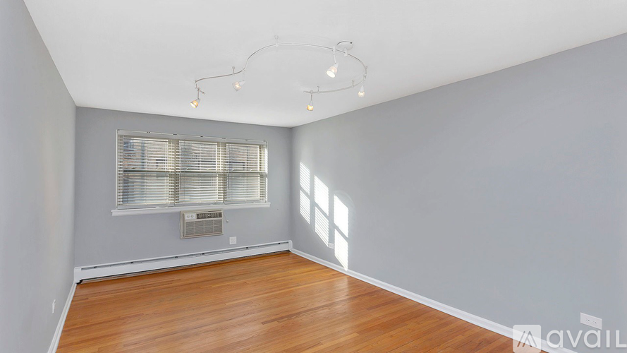 A room with wooden floors and a window with blinds.