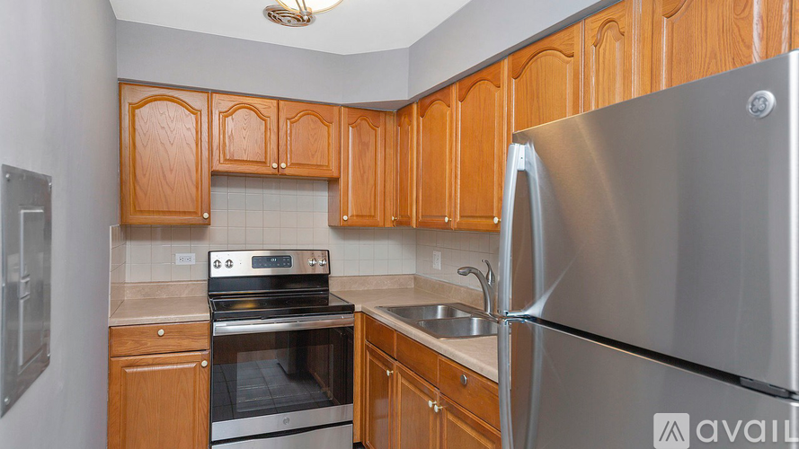 A kitchen with wooden cabinets and a stainless steel refrigerator.