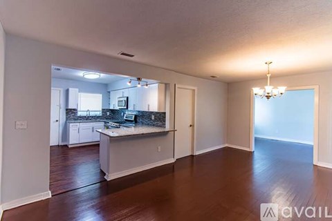 A kitchen with a granite countertop and a dining area with a chandelier.