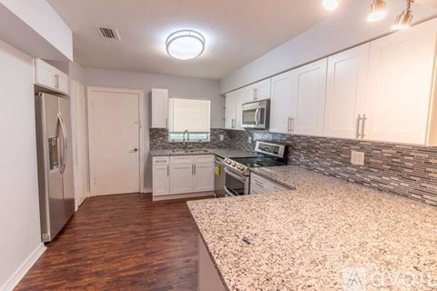 A kitchen with white cabinets and a granite countertop.