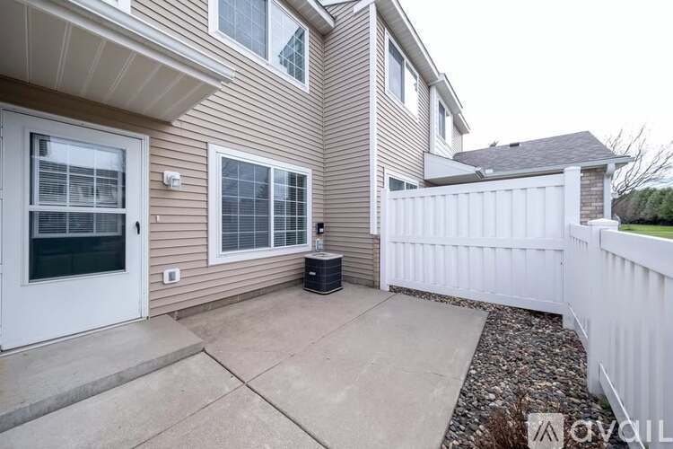 A house with a white fence and a black trash can in front of it.