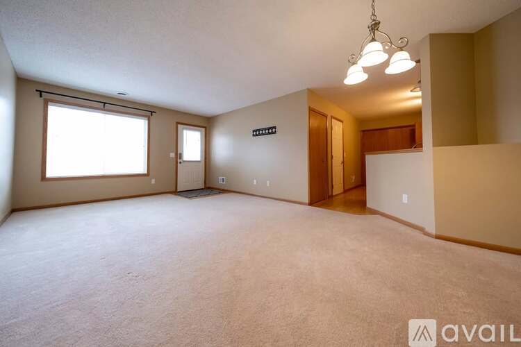 A spacious room with a carpeted floor and a chandelier hanging from the ceiling.