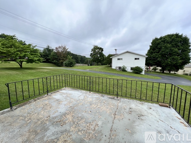 A white house is surrounded by a black fence and green trees.