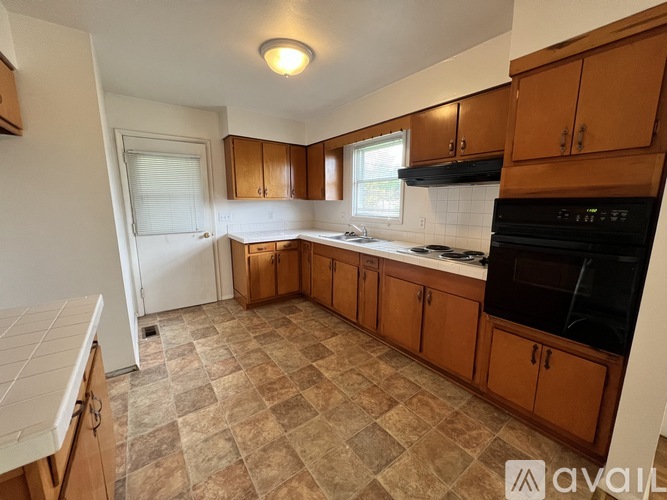 A kitchen with brown cabinets and a black oven.