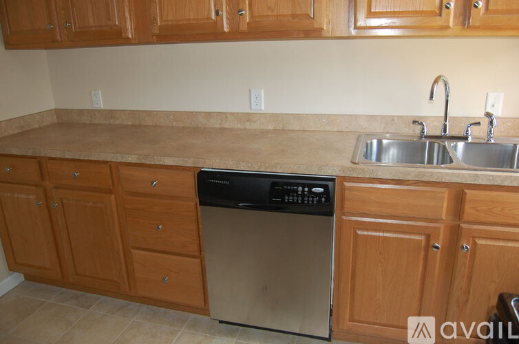 A kitchen with wooden cabinets and a stainless steel dishwasher.