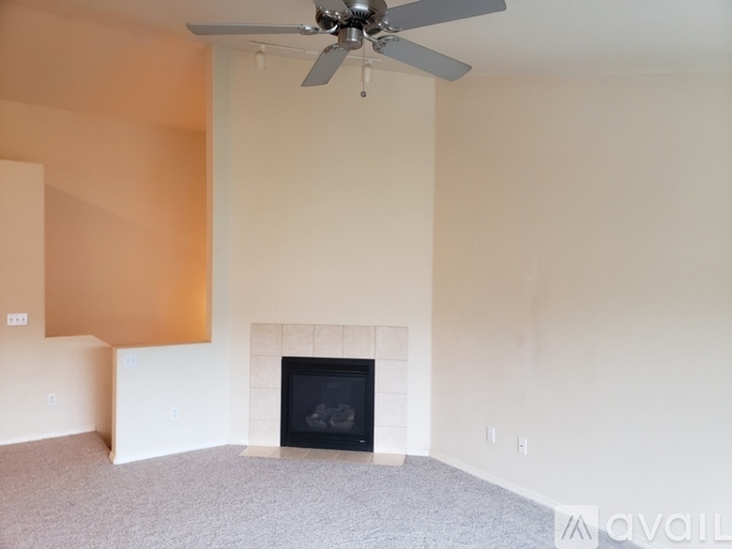 A room with a fireplace and a fan on the ceiling.