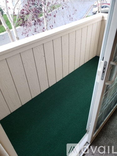 A balcony with a green carpet and white walls.