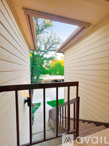 A balcony with a view of a green lawn and trees.