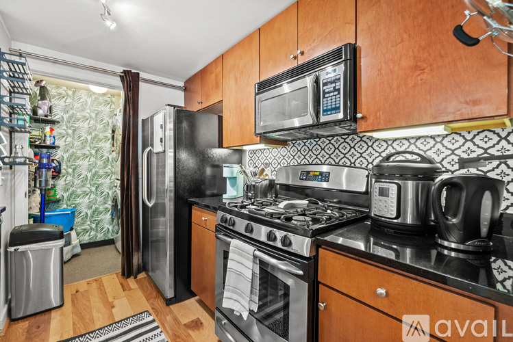 A kitchen with wooden cabinets and a black fridge.