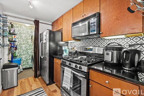 A kitchen with wooden cabinets and a black fridge.