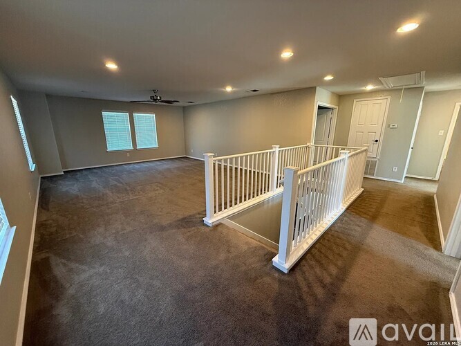 A spacious room with a white railing and carpeted floor.