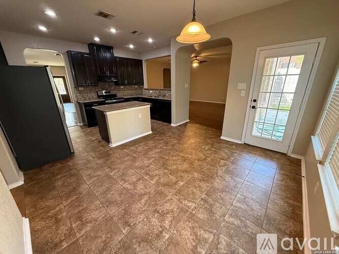 A kitchen with black cabinets and a white island.