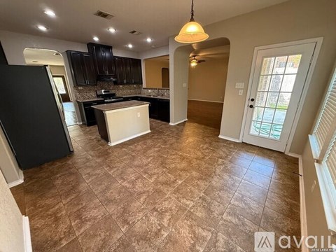 A kitchen with black cabinets and a white island.